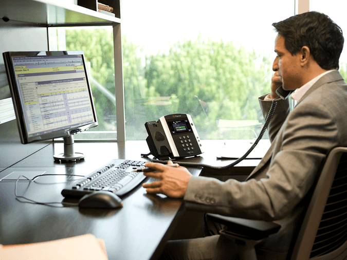 man on his desk phone looking at computer