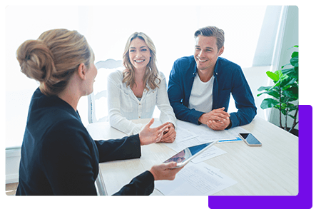 Insurance agent speaking to a couple in an office with a white desk - net2phone Canada - Business VoIP Phone System