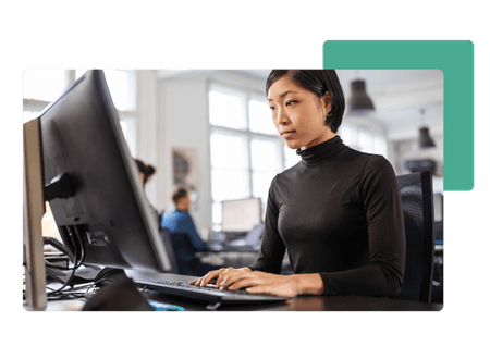 Woman in black shirt typing on keyboard looking at desktop computer in an office - net2phone Canada - Business VoIP Phone System