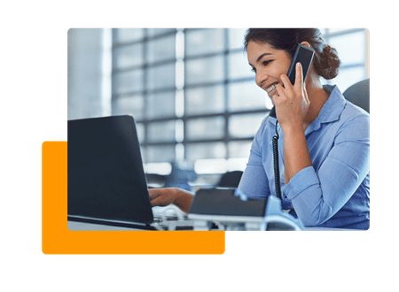 Woman in office talking on phone and typing on laptop - net2phone Canada - Business VoIP Phone System