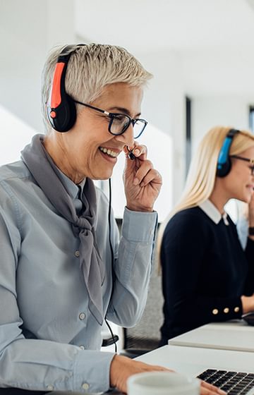 three women in business attire with headsets working in a call centre seated in front of laptops