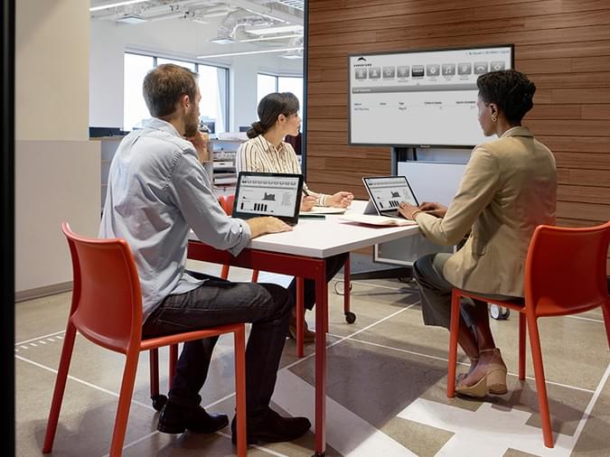 people sitting at a desk looking at a dashboard