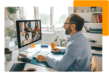 Man working at desk talking to employees through video conference on computer screen - net2phone Canada - Business VoIP Phone System