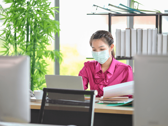 an image of a woman wearing a mask at her desk