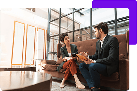 Man and woman sit on leather bench in office lobby - net2phone Canada - Business VoIP Phone System