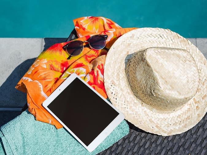 hat, ipad, towel and sunglasses at the beach