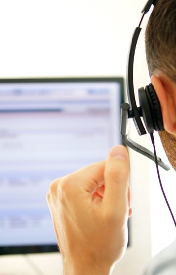 Man wearing headset looking at desktop computer - net2phone Canada - Business VoIP Phone System