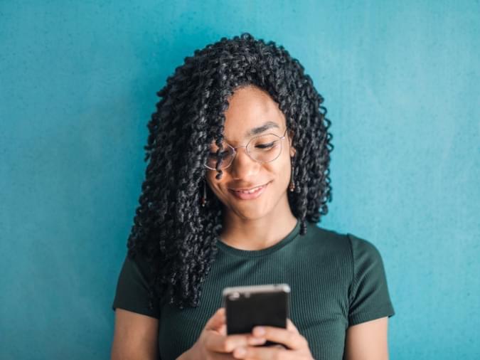 A woman in front of a wall on her cell phone