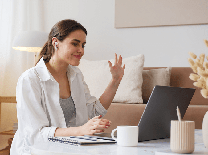 A woman video conferencing at her computer in her living room