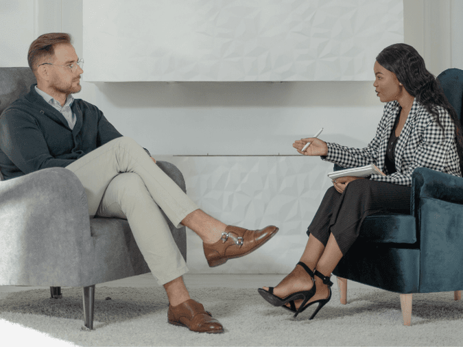 Two business people sitting in chairs talking