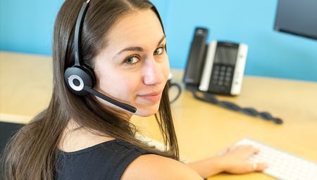 Brunette woman wearing phone headset looking at camera - net2phone Canada - Business VoIP Phone System