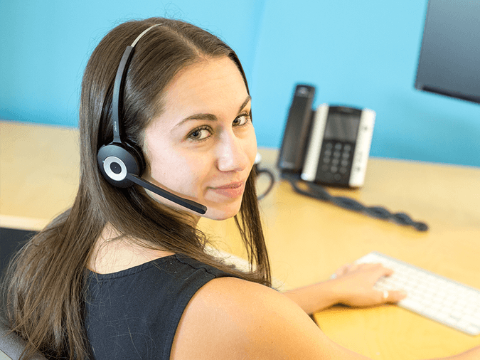 Brunette woman wearing phone headset looking at camera - net2phone Canada - Business VoIP Phone System
