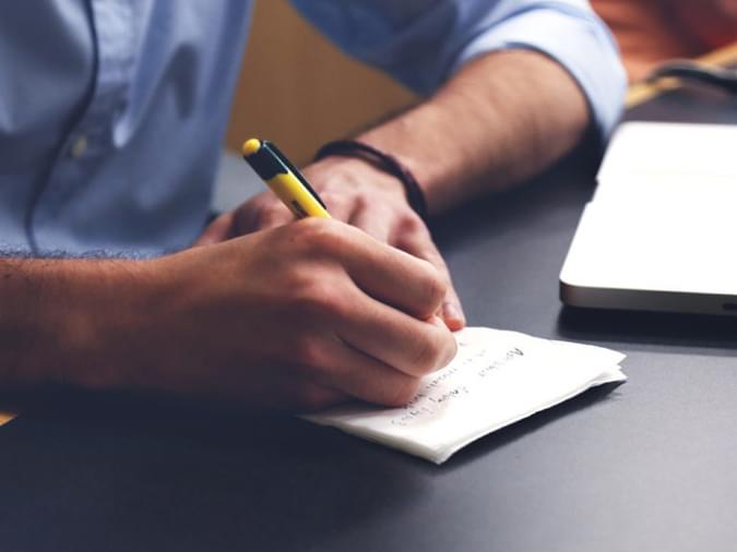 man writing notes with pen - net2phone Canada - Business VoIP Phone System