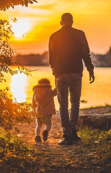 Man holding a childs hand overlooking a lake at sunset - net2phone Canada - Business VoIP Phone System