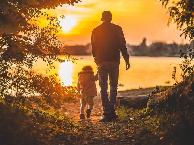 Man holding a childs hand overlooking a lake at sunset - net2phone Canada - Business VoIP Phone System