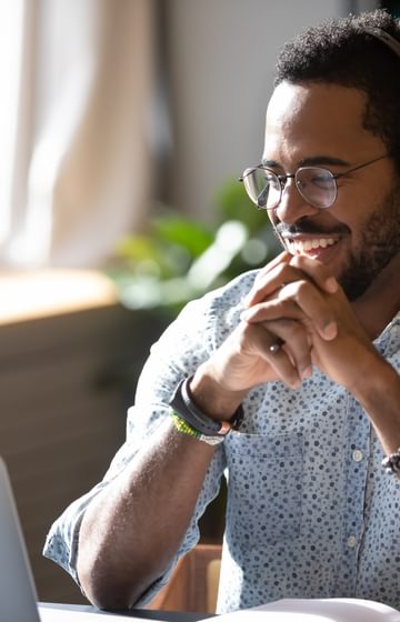 man with headset on smiling while seated in front of laptop in home office