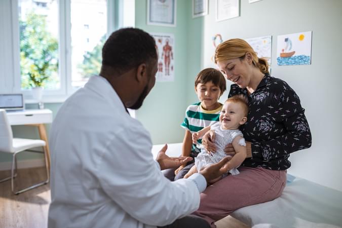 Doctor tending to baby patient with mom and young boy - Healthcare Industry- net2phone Canada - Business VoIP Phone System