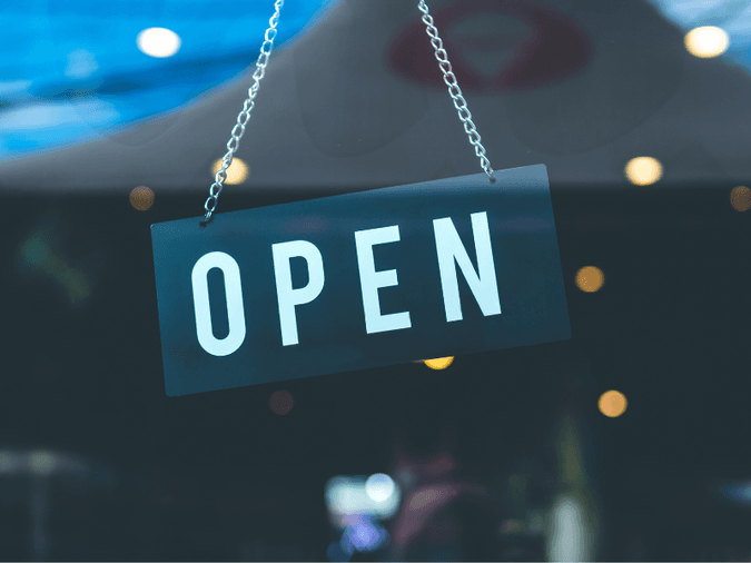 Picture of an open door sign hung from the entrance of a store