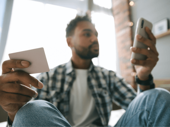 A man on a cellphone holding a business card - net2phone Canada - Business VoIP Phone System