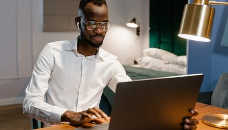 Man working remotely from a desk in his bedroon