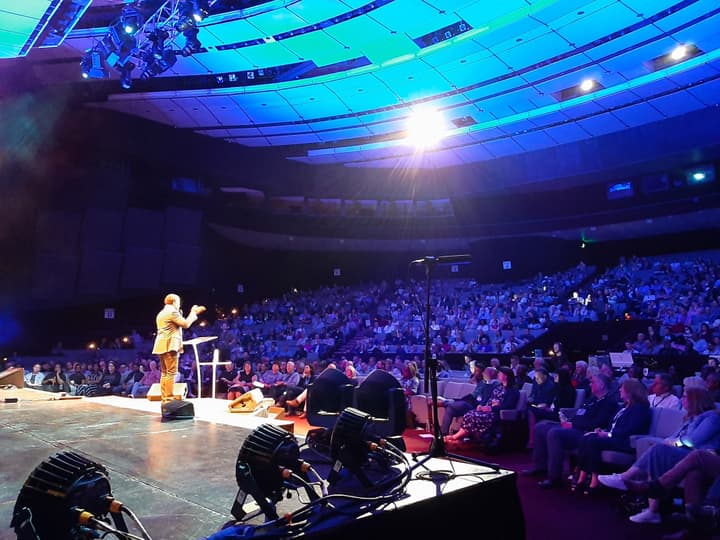 A speaker on stage talking to a full auditorium