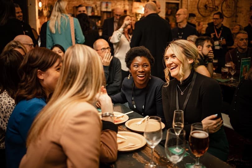 A group of women sitting around a table laughing in a busy pub
