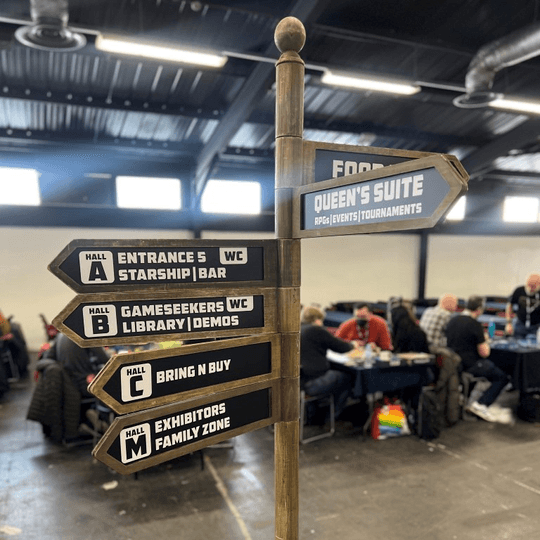 Wooden sign post with directional arrows pointing at different gaming activities