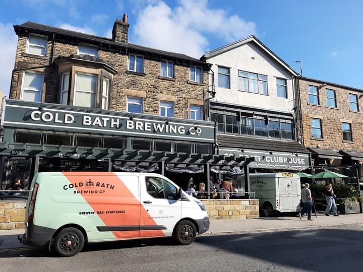 A patio on the roadside with the sign Cold Bath Brewing Co. and a branded van parked in front of it