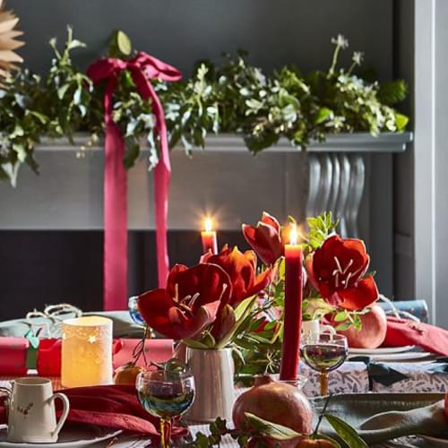 Christmas table setting with candles, flowers and ribbons