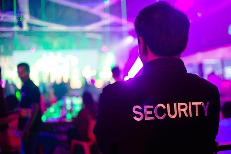 Man in security uniform standing in front of a crowded event hall