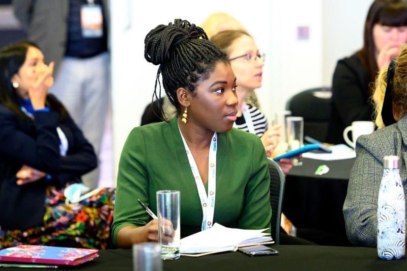 A women sitting among other delegates at a conference