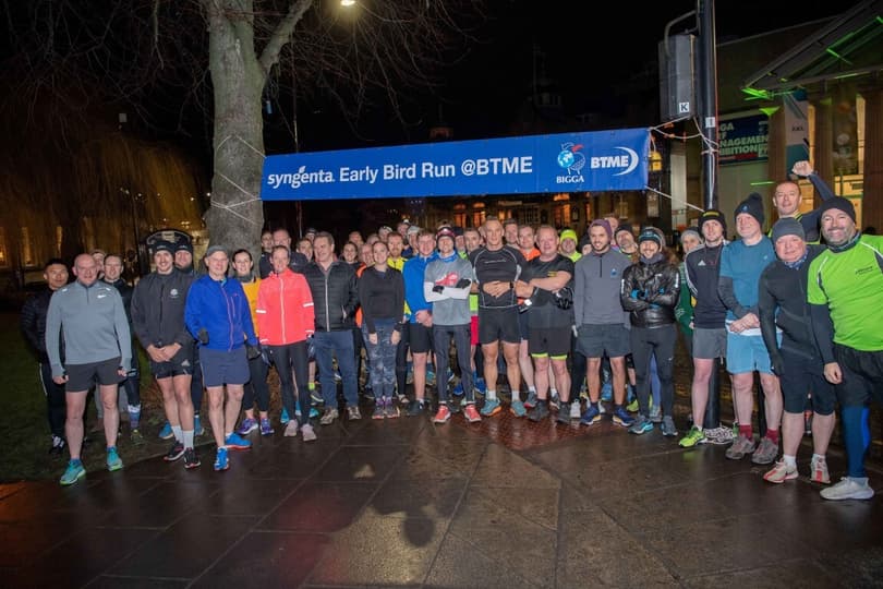A group of people participating in the early bird run event in Harrogate, happily posing in front of a banner.