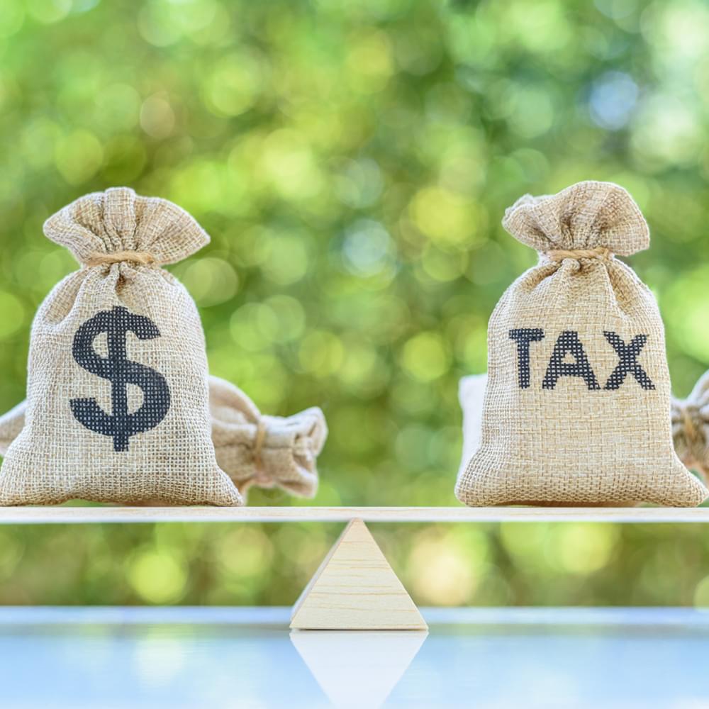 Tax, dollar money bags on a simple balance scale stock photo