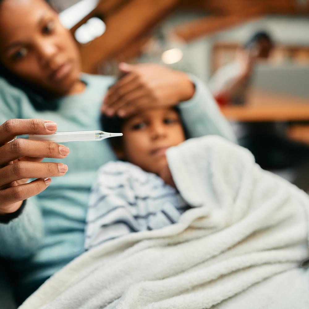 Close-up of African American mother using thermometer and measuring temperature or her sick son at home. Alabama News