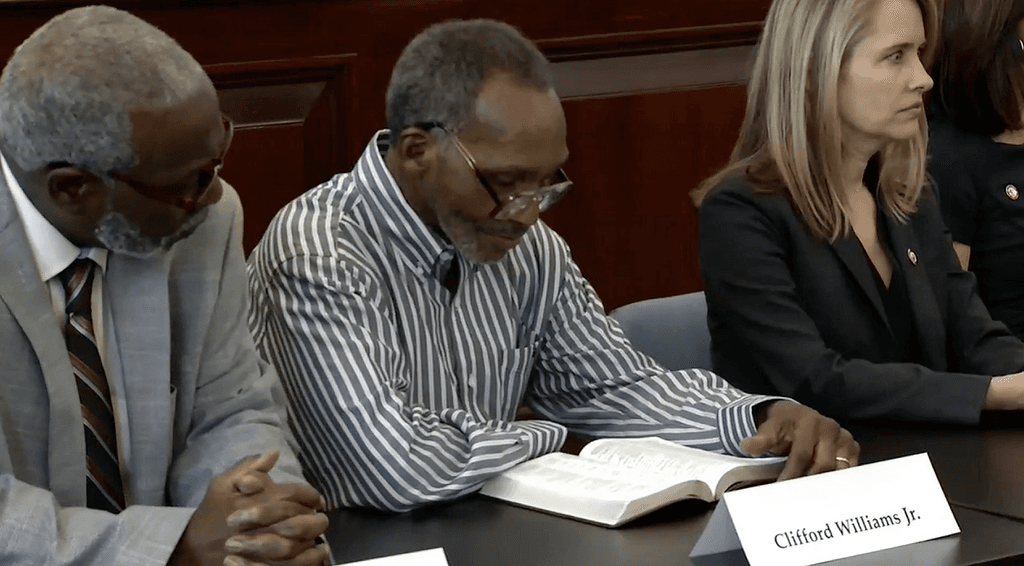 Clifford Williams, Jr. (center) reads from his Bible during the news conference announcing his exoneration. His nephew, Nathan Myers (left) was also exonerated. To their right is Shelley Thibodeau, director of the Florida Fourth Judicial Circuit State Attorney’s Conviction Integrity Unit.