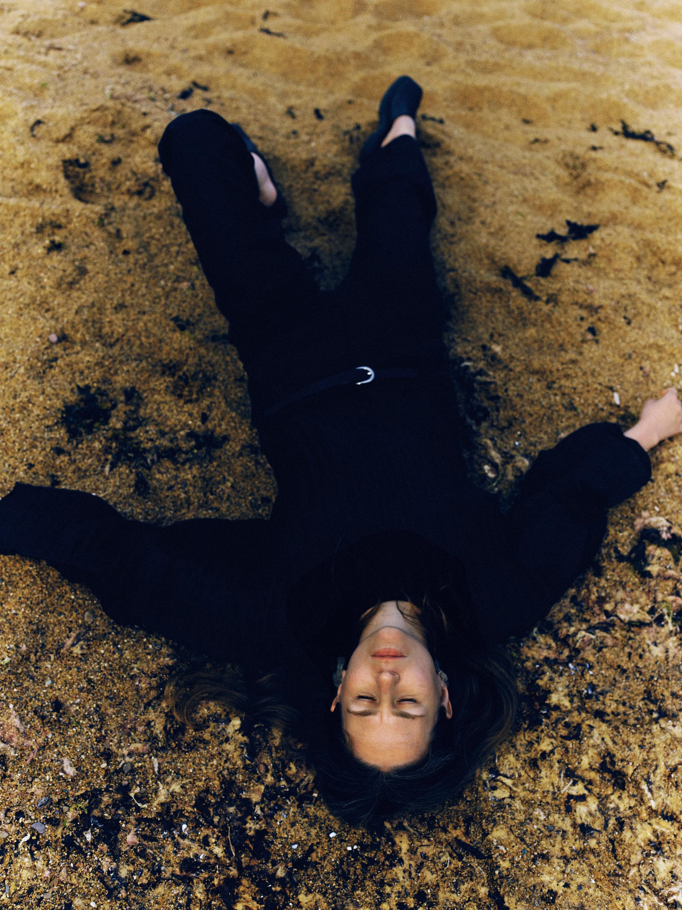 Alice Boman lying flat on the ground, dressed all in black