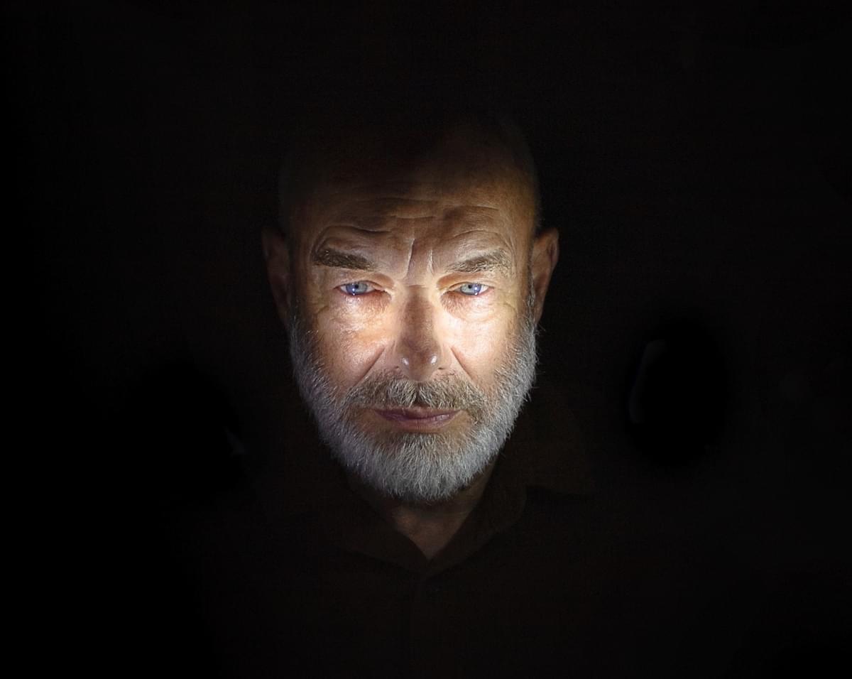 Brian Eno black background light highlighting face