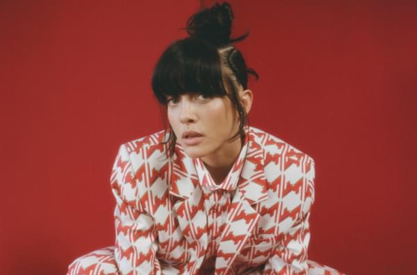 Noga Erez crouching in red patterned suit