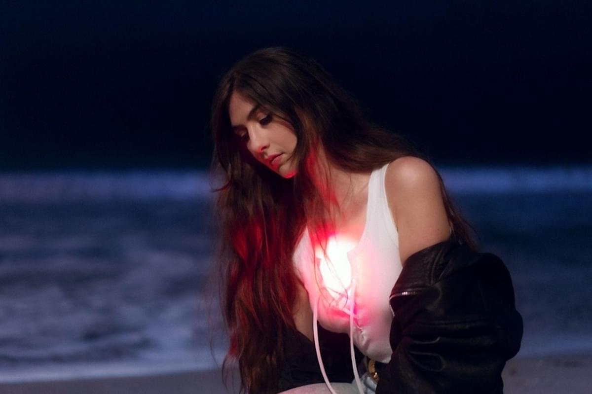Weyes Blood on a beach at night for And In The Darkness, Hearts Aglow album announce
