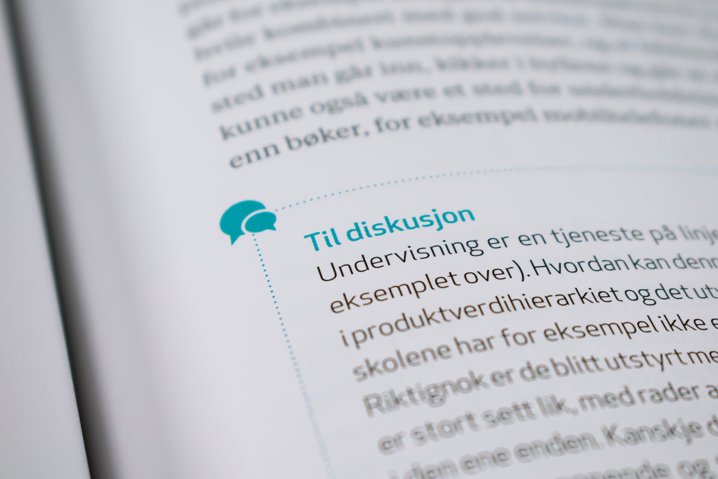 Bildet viser et nærbilde av en bokside. Det er en turkis stiplet linje rundt en tekst som har tittelen «Til diskusjon». Øverst i venstre hjørne av boksen er et ikon: to turkise snakkebobler.