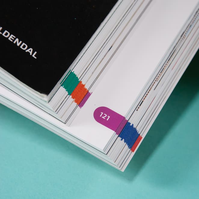 Bildet viser sidetallene i boken sett fra kanten av boken. Sidetallene har hver sin bakgrunnsfarge.
