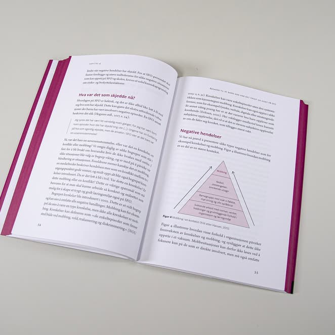 Bildet viser et oppslag av en bok tatt ovenfra. Det er tekst på begge sider. På høyre side er det en figur, som viser en trekant. Det er farget yttermarg.