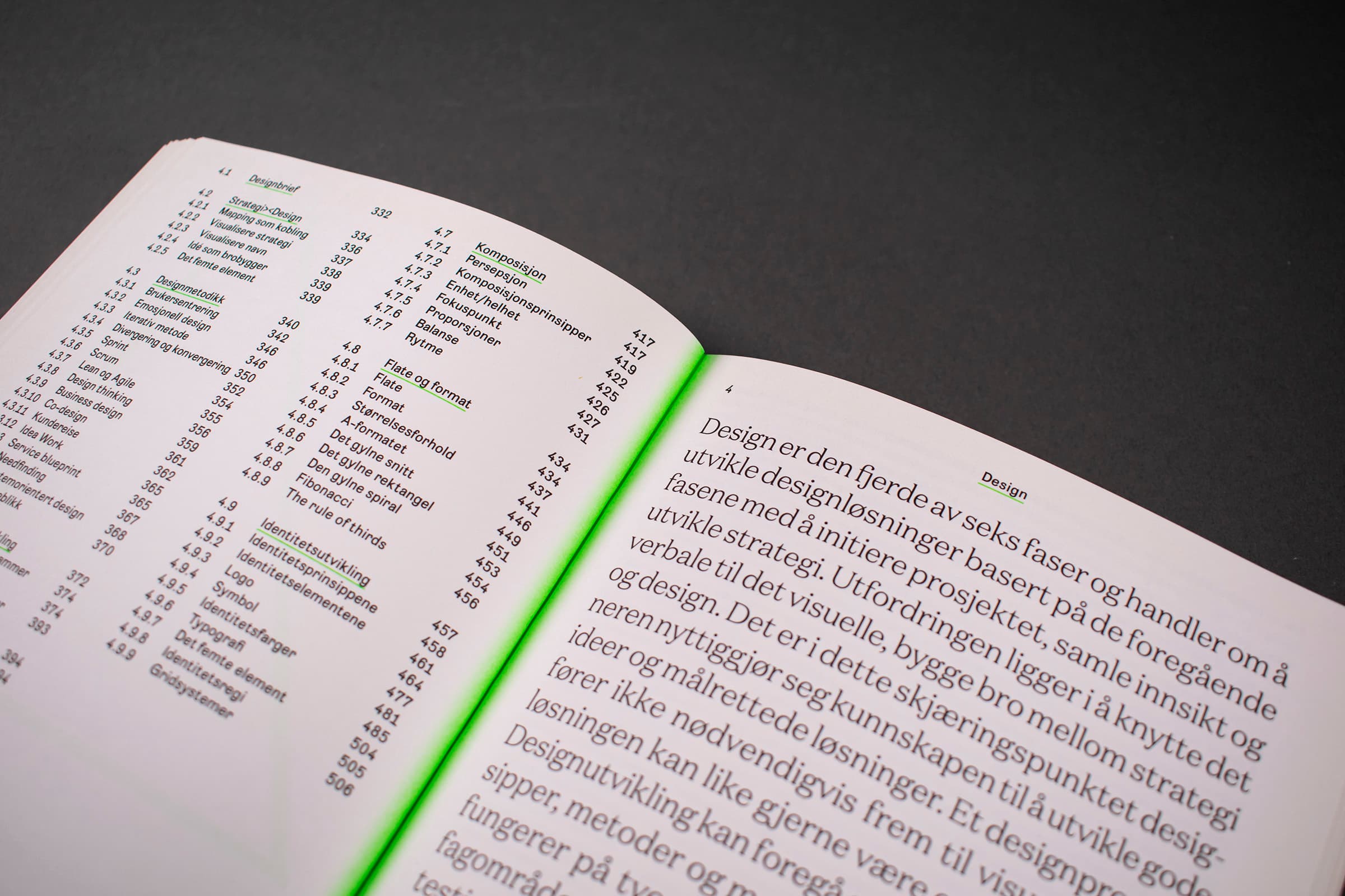 Bildet viser et oppslag av Design og Strategi. På venstre side er det en innholdsfortegnelse, mens det er tekst på høyre side. I midten av boken, i bretten, er det et neon-grønt fargefelt som "gløder".