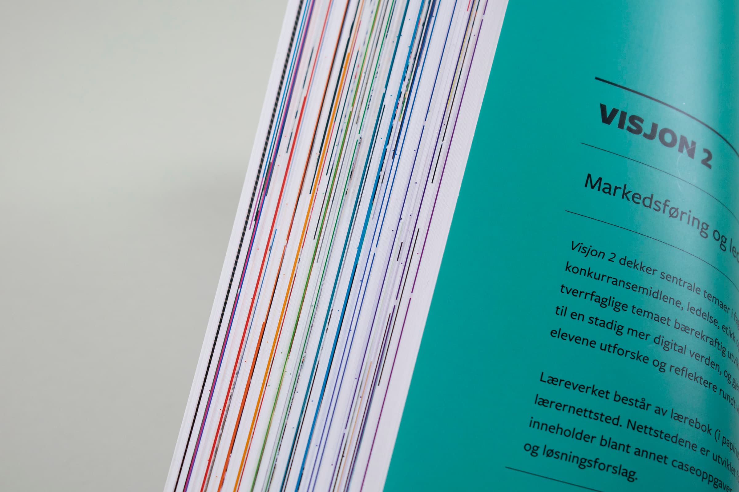 Bildet viser et nærbilde av kanten på boka. Her ser man at de ulike kapitlene har ulik farge på kanten av sidene – fra rød til grønn og blå.