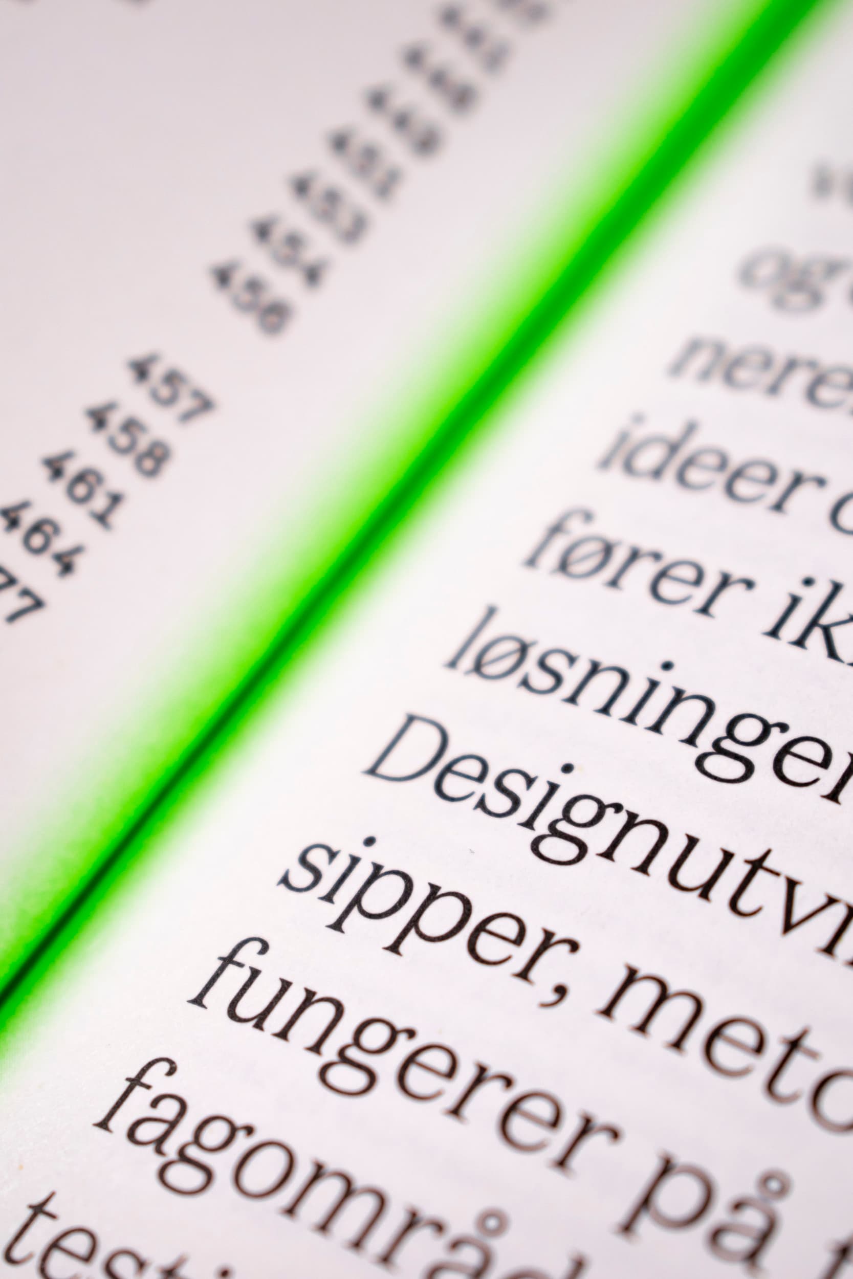 Bildet er et nærbilde av brettet mellom to sider av Design og Strategi. Det er tekst på begge sider, mens i midten er det et neon-grønt fargefelt, som optisk gløder opp fra midten av boken.