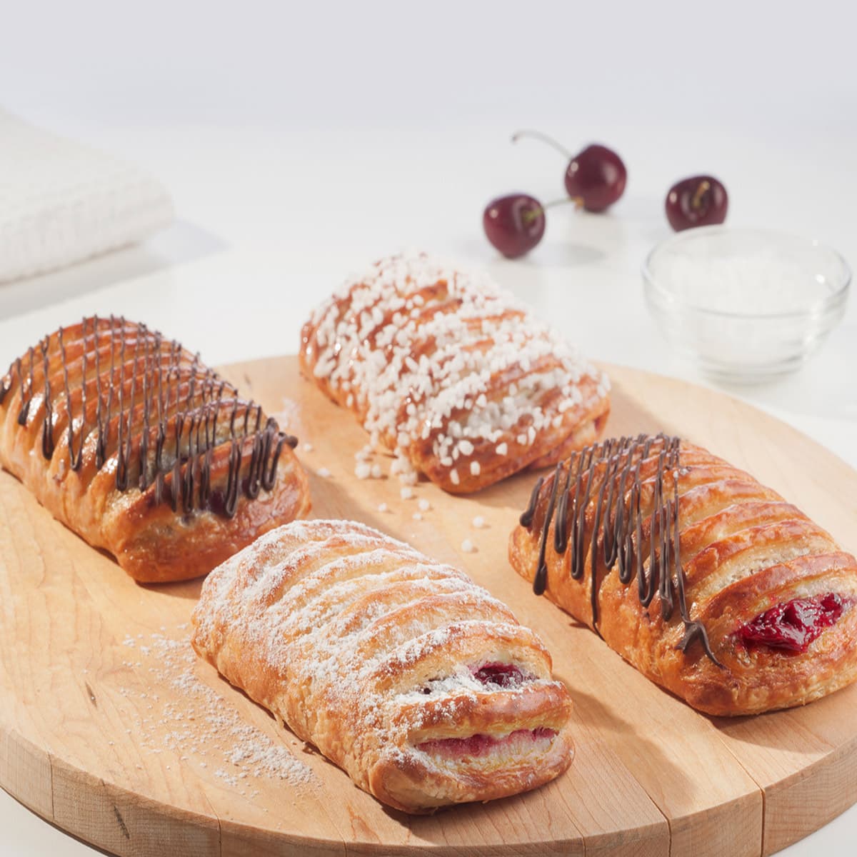 four greek yogurt cherry danishes topped with sugar and chocolate