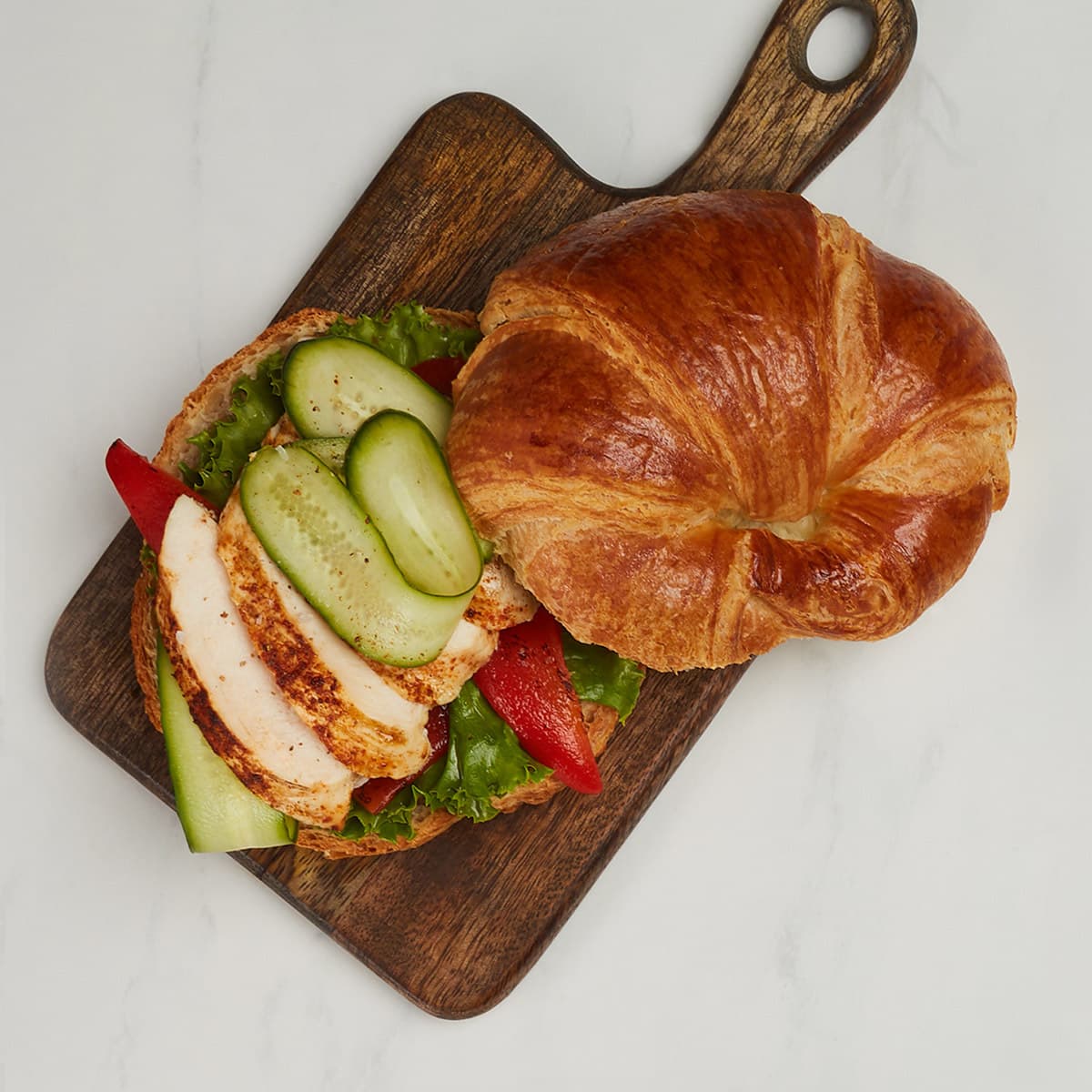 sliced curved butter croissant sandwich on a board