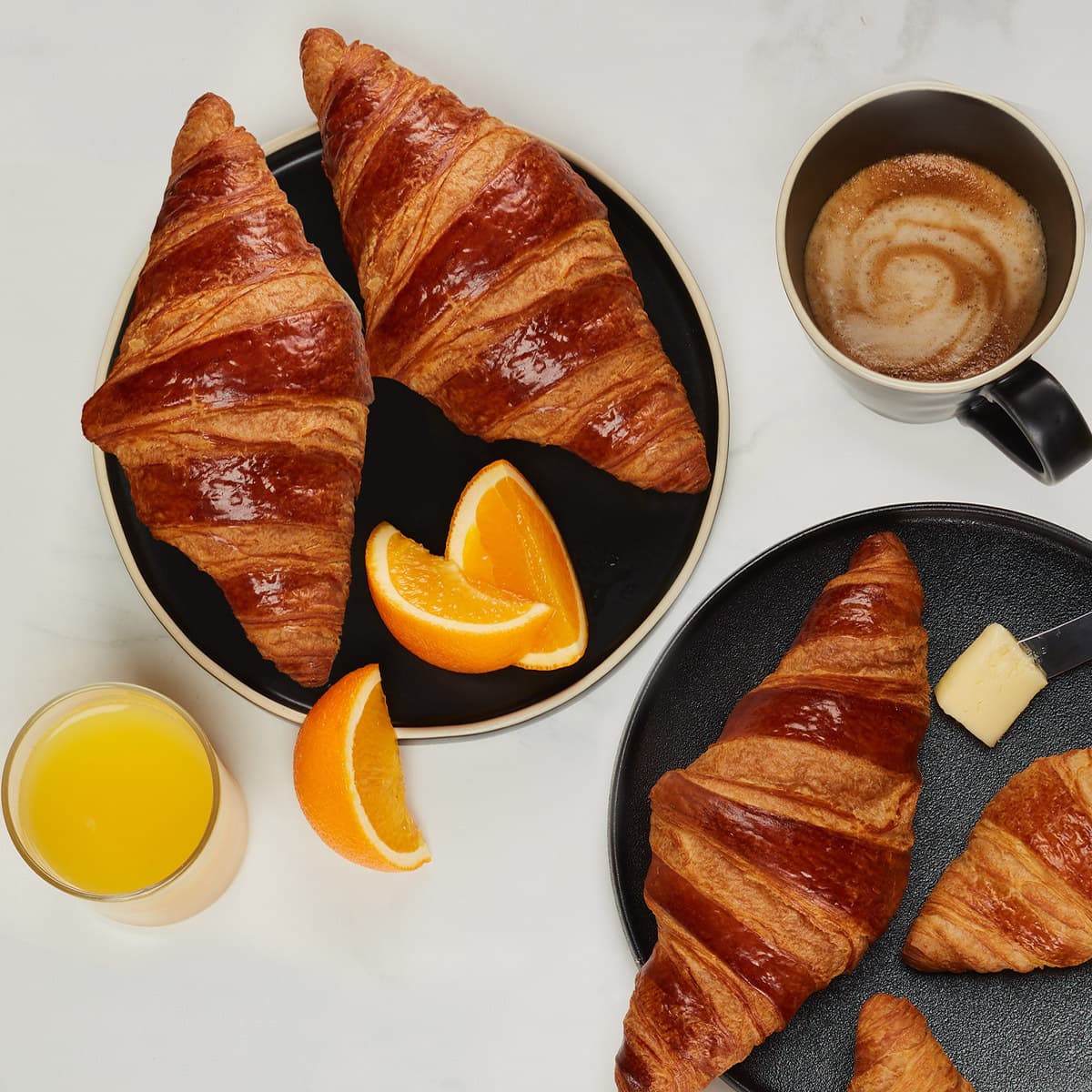 trois croissants parfaits tout beurre avec un jus d'orange et un café