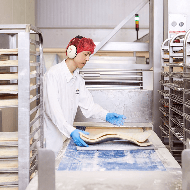 bridor employee flattening uncooked dough