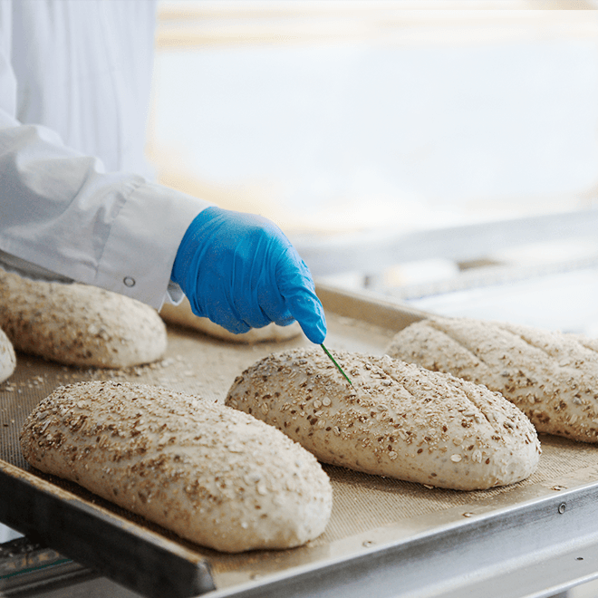 employee scoring a loaf of bread
